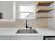 Modern kitchen sink with white countertops, floating wood shelves and neutral-toned backsplash at 637 N Quartz Ln, Fortville, IN 46040
