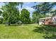 Expansive backyard featuring lush green grass, mature trees, shed, and a fire pit at 6799 Lakeshore Dr, Avon, IN 46123