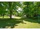 Lush backyard with mature trees, manicured lawn, shed, and view of the home at 6799 Lakeshore Dr, Avon, IN 46123