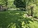 Expansive backyard featuring a lush lawn, mature trees, and a charming pergola with climbing plants at 7015 Westlake Rd, Indianapolis, IN 46214