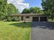 Charming brick ranch with an attached two-car garage, mature trees, and a well-manicured lawn at 7015 Westlake Rd, Indianapolis, IN 46214