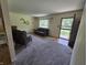 A bright living room featuring neutral walls and carpet, with access to the front door and kitchen at 7015 Westlake Rd, Indianapolis, IN 46214