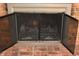 Rustic brick fireplace with a black metal screen and doors at 7443 Country Brook Dr, Indianapolis, IN 46260