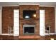 Close up shot of a brick fireplace with built-in shelving and a mounted television at 7443 Country Brook Dr, Indianapolis, IN 46260