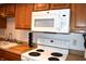 This kitchen features wooden cabinets, a white microwave, and a white electric stovetop at 7443 Country Brook Dr, Indianapolis, IN 46260