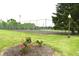 Community tennis court surrounded by flowers and a bright green lawn at 7443 Country Brook Dr, Indianapolis, IN 46260