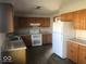 Spacious kitchen featuring wood cabinetry, white appliances, and laminate flooring at 1045 Springway Dr, Shelbyville, IN 46176