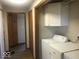 Laundry room with white washer and dryer, overhead cabinets and vinyl plank flooring at 1045 Springway Dr, Shelbyville, IN 46176