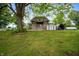 Back exterior shot of the house showing the balcony, a shed, and a well maintained spacious grassy area at 11720 S County Road 396 E, Muncie, IN 47302