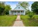 Charming light blue home featuring a quaint porch with hanging flower baskets and a stone walkway at 11720 S County Road 396 E, Muncie, IN 47302