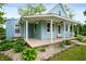 Charming light blue home featuring a porch with flower baskets and beautifully landscaped stone garden at 11720 S County Road 396 E, Muncie, IN 47302
