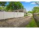 Long asphalt driveway with a white vinyl fence leading to the gray home at 1240 Hamilton Dr, Noblesville, IN 46060
