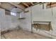 Unfinished basement with concrete floors, small window, support beam and utility sink at 1601 Southern Ave, Beech Grove, IN 46107