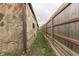 Side yard featuring stone house exterior, grass, wooden fence, and rain gutter at 1601 Southern Ave, Beech Grove, IN 46107