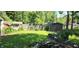 Lush backyard featuring a shed, vibrant green grass, scattered branches and surrounded by mature trees at 1619 Crest Ct, Indianapolis, IN 46214