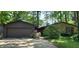 Charming home featuring a stone facade and a two-car garage surrounded by mature trees and lush landscaping at 1619 Crest Ct, Indianapolis, IN 46214