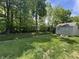 Grassy backyard featuring a shed with double doors and a small concrete stoop under a blue sky at 167 Hilltop Farms Blvd, New Whiteland, IN 46184