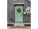 Close-up of a mint-green front door with a 'Welcome' wreath and modern accents at 1841 New St, Indianapolis, IN 46203