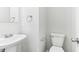 Compact half bathroom featuring a pedestal sink, toilet, and neutral wall color at 1936 Southernwood Ln, Indianapolis, IN 46231