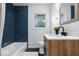 Modern bathroom features blue tiled shower, black and white flooring, and wood vanity at 2105 Mayfair Dr, Indianapolis, IN 46260