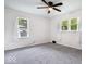 Spacious bedroom with a ceiling fan, two windows, and carpeted floors at 2105 Mayfair Dr, Indianapolis, IN 46260