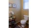 Cozy half-bathroom with a white toilet, wooden floor, and a side table for decorative items at 2445 N Delaware St, Indianapolis, IN 46205
