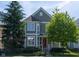 Charming two-story home with a red door, black fence, and mature trees in a well-maintained yard at 2445 N Delaware St, Indianapolis, IN 46205