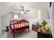 This bedroom features wood trim, a ceiling fan, one window, a bed with a red comforter and white floors at 3360 Main St, Plainfield, IN 46168