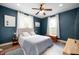 This bedroom features a ceiling fan, blue walls, two windows, and a bed with a blue quilt at 3360 Main St, Plainfield, IN 46168