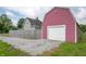 View of the detached garage with a barn-style roof, alongside a gravel driveway at 3360 Main St, Plainfield, IN 46168