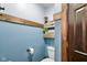 A cute half bathroom with wooden shelving and blue walls, complete with a toilet and toilet paper holder at 3480 W Broadus Dr, North Vernon, IN 47265