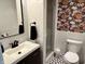 Bathroom with floral accent wall, white tile, black fixtures, a toilet, a sink, and shower at 377 4Th E Ct, Carmel, IN 46033