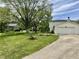 Charming front yard with mature trees, green lawn, a paved driveway, and an attached two-car garage at 377 4Th E Ct, Carmel, IN 46033