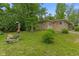 The stone house with an attached garage is next to an outdoor table set on a grassy lawn at 3841 S Sherman Dr, Indianapolis, IN 46237