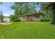A stone-clad house sits on a lush green lawn surrounded by mature trees and landscaping at 3841 S Sherman Dr, Indianapolis, IN 46237
