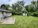 A spacious backyard featuring a concrete patio, well-maintained lawn, and a storage shed amidst mature trees at 4004 N Ball Ave, Muncie, IN 47304