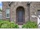 Close-up of the front door framed by an archway, surrounded by lush greenery and manicured shrubs at 4689 Muscatine Way, Westfield, IN 46062