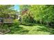 View of the backyard featuring a lush lawn with a patio area and a brick wall with shrubbery at 5350 Chico Grey Dr, Indianapolis, IN 46237