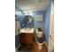 A compact bathroom with a blue tiled wall, decorative mirror, and a wood-look floor at 5920 Copeland Mills Dr, Indianapolis, IN 46221