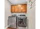 This laundry room includes modern silver washer and dryer with wood cabinets for storage at 6168 Pine Bluff Dr, Avon, IN 46123