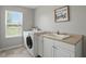 Bright laundry room with a large window, washer, dryer, and utility sink at 6552 Hunters S Rdg, Zionsville, IN 46077
