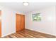 Cozy bedroom with wood-look floors, neutral walls, a window view, and a wood closet door at 7050 N County Road 650 E, Brownsburg, IN 46112