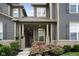 Inviting front porch with brick columns, flowering bushes, and seating area at front door at 7152 Cherry Creek Blvd, Carmel, IN 46033