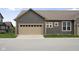 Attached garage with a tan door and gray siding with white trimmed windows above at 7152 Cherry Creek Blvd, Carmel, IN 46033