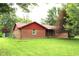 Brick home with red trim and a well-manicured lawn surrounded by lush greenery at 7931 Guion Rd, Indianapolis, IN 46268