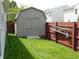 A backyard shed sits on a well manicured green lawn enclosed by a privacy fence and a ladder at 8346 Weathervane Cir, Indianapolis, IN 46239