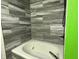 Soaking tub with gray-scale tile surround and modern fixtures in a bright bathroom at 892 Millbrook Dr, Avon, IN 46123