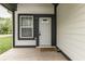 Close-up of a welcoming front porch with a wooden deck, stylish white door, and black trim at 9317 E 36Th Pl, Indianapolis, IN 46235