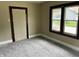 Bedroom showcasing new gray carpeting and two windows, with neutral walls and a wood-trimmed door at 1020 E 30Th St, Anderson, IN 46016