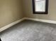 Corner view of room showing gray carpet, a window, neutral paint and a white baseboard at 1020 E 30Th St, Anderson, IN 46016